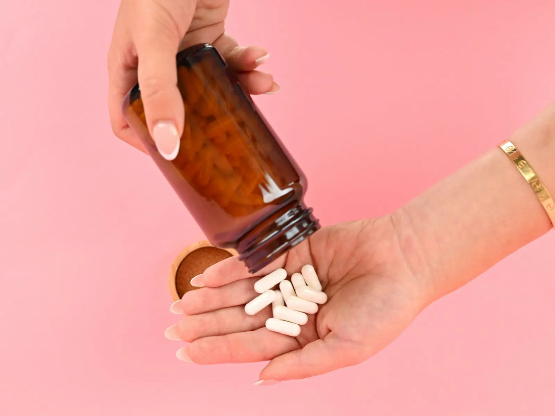 A hand pouring white supplement capsules from an amber bottle — representing the growing market of vitamins and supplements and the question of which ones are actually worth taking